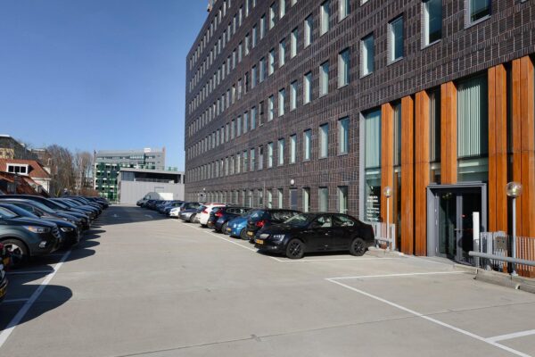 Parkeerterrein naast het Chelsea Building aan de Laan van Zuid Hoorn met geparkeerde auto's en moderne kantoorgebouwen.